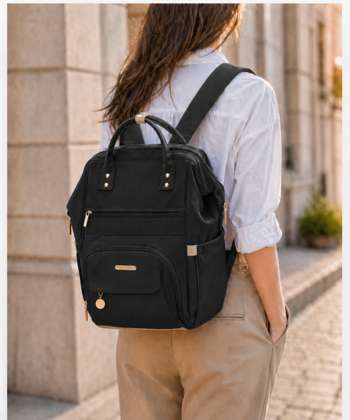 Femme portant le sac à langer NEVA Paris noir en mode sac à dos dans une rue parisienne