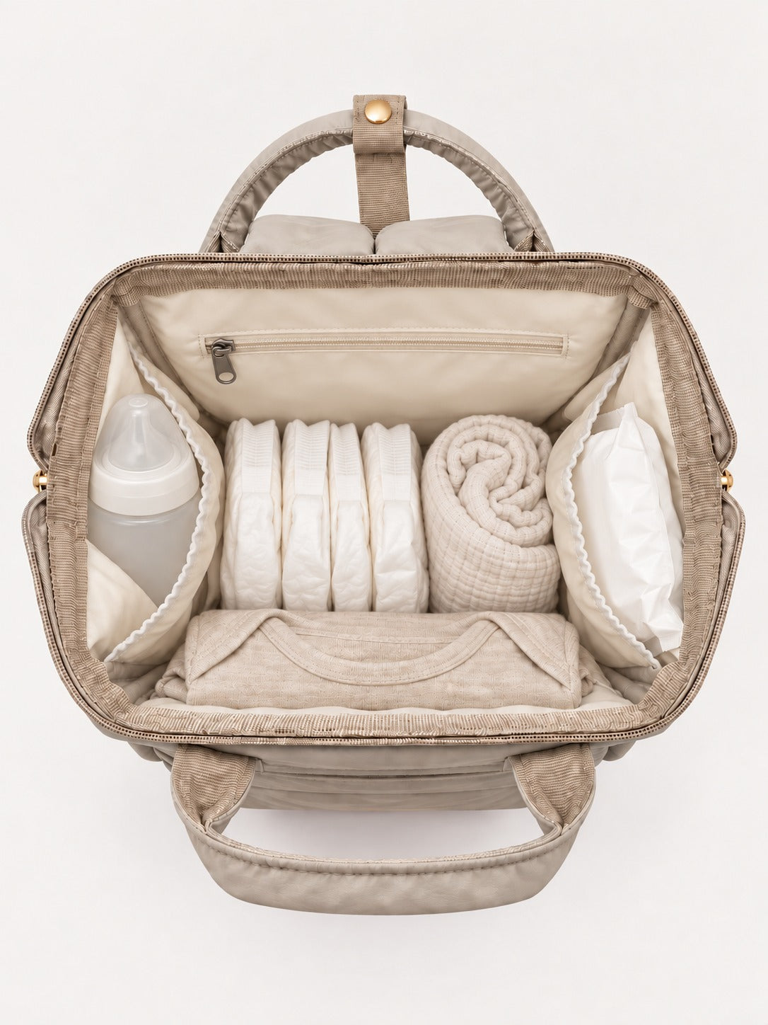 Sac à langer NEVA L'Essentiel ouvert et rempli : biberon, lingettes, couches et change rangés dans les poches intérieures.